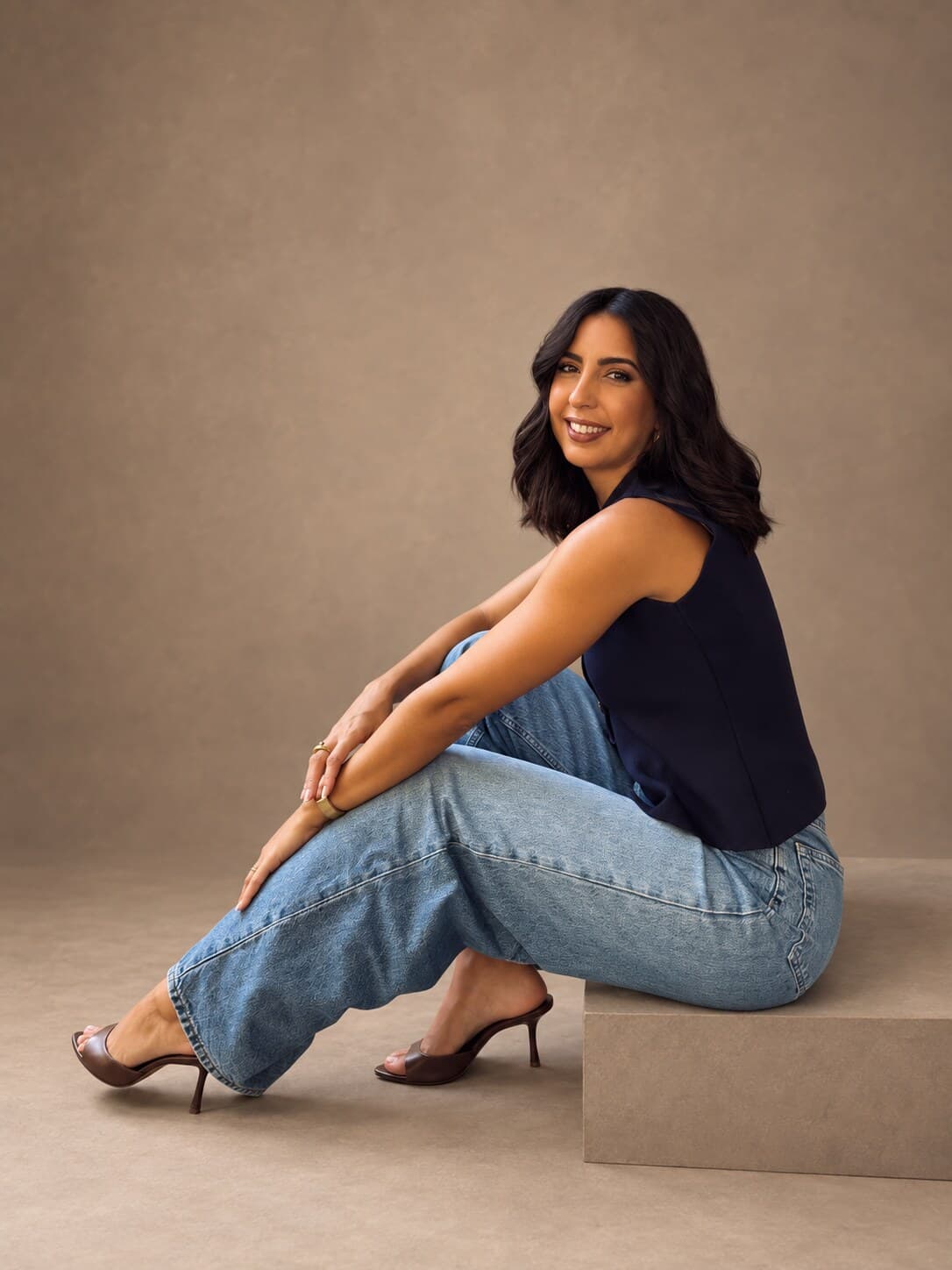 Olga Muelas, creadora de Dobledos, sentada y sonriente en un estudio de tonos tierra